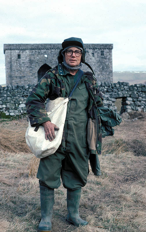 Man wearing camo standing in front of an old stone building